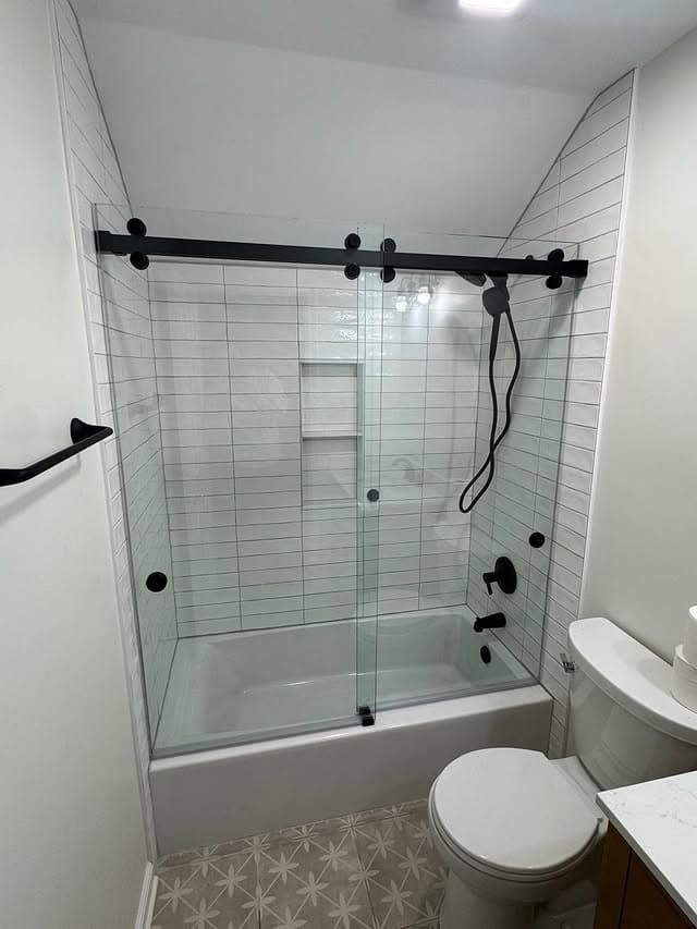 Bathroom with a black sliding shower door and white tile